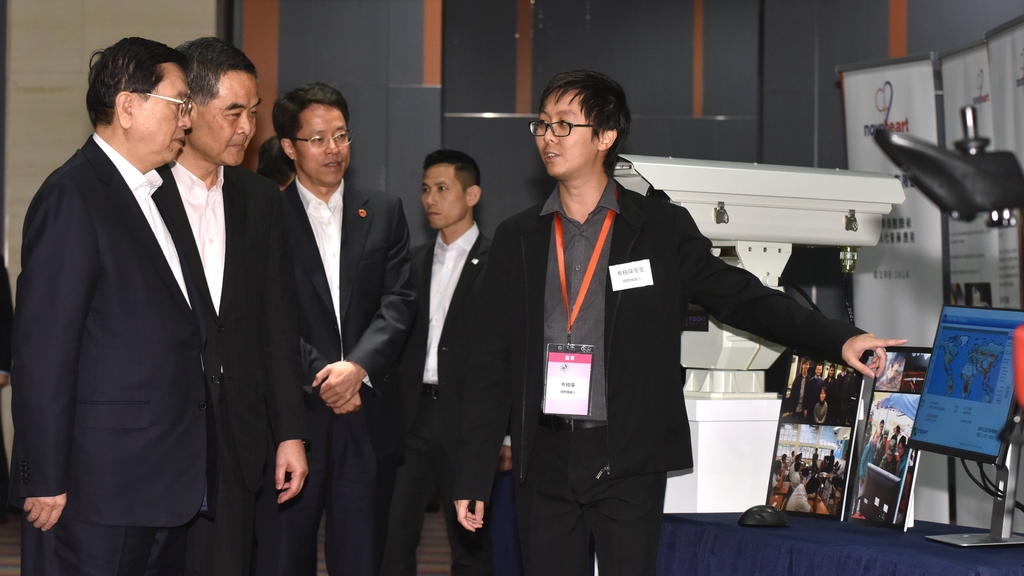 張德江（左一）今日在香港科學園與本地創科初創青年企業家會面，其中一位岑棓琛（右一）向他介紹一座結合不同機械人技術而製成的防火機械人。（照片由政府新聞處提供）