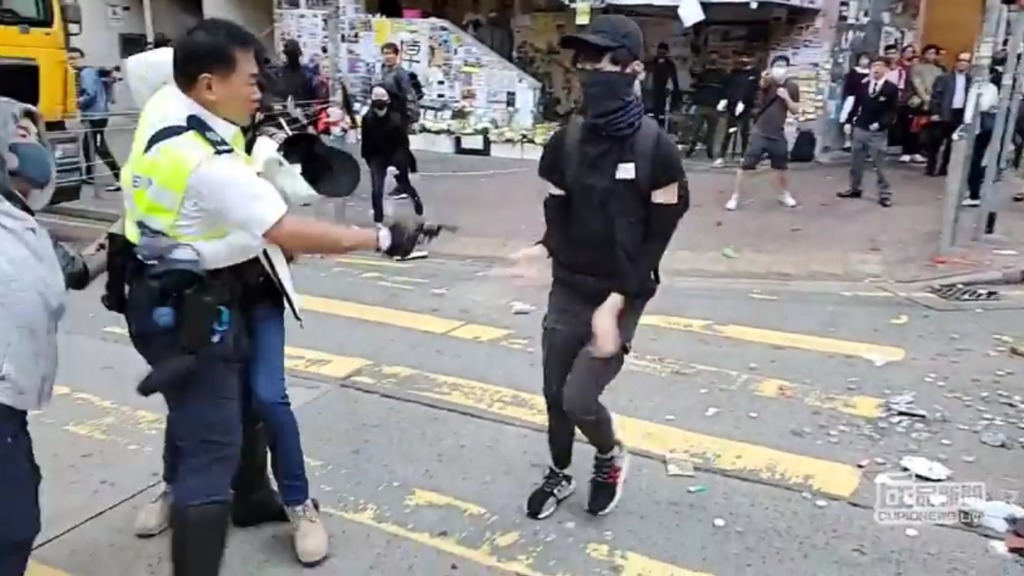 有示威者於西灣河堵路，交通警與蒙面示威者發生爭執，有交通警拔槍並至少開三發實彈真槍，其中一名男子中槍。（「丘品創作」fb影片截圖)