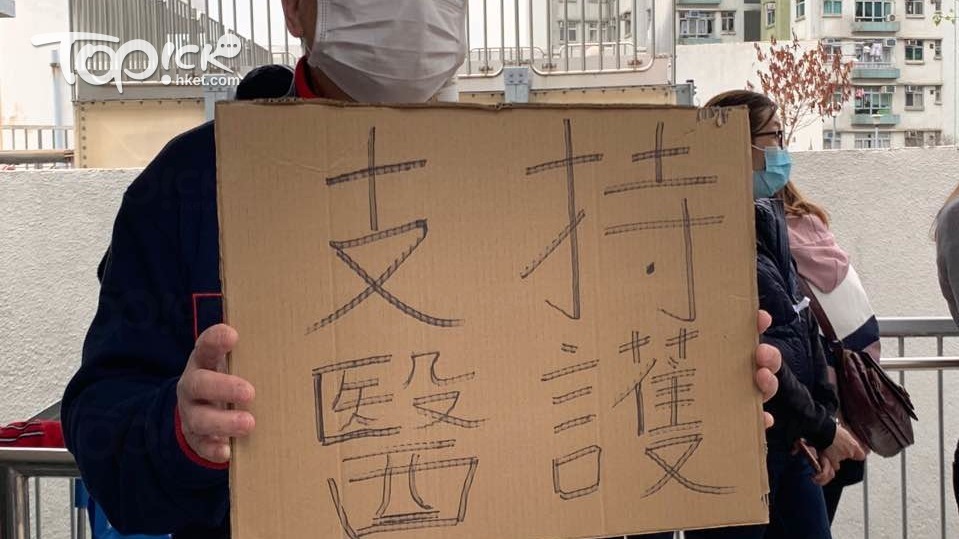 鄧先生高舉自製紙牌，寫上「支持醫護」的字句。（經濟日報記者攝）