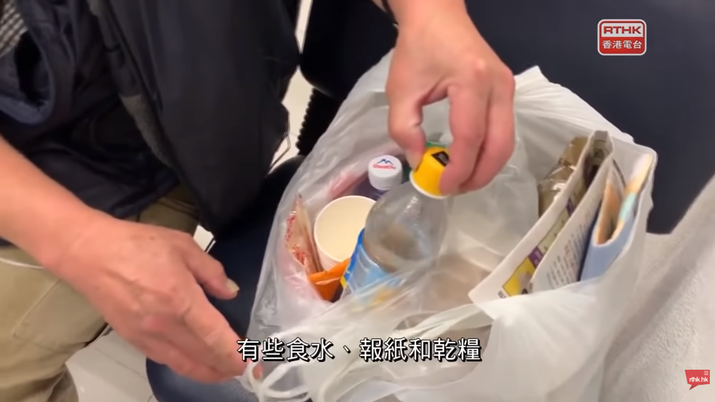 林伯以白膠袋盛載全副家當，內有樽裝水及馬經等。（影片截圖）