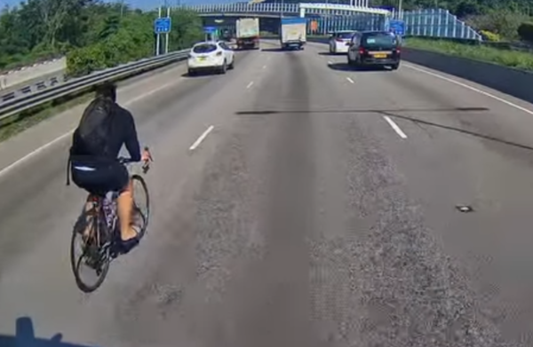 單車友未佩戴任何防護裝備,加之兩側皆是大型貨車,易形成視線盲區,稍有不慎便可能發生意外。(取自Facebook「車cam L」群組)