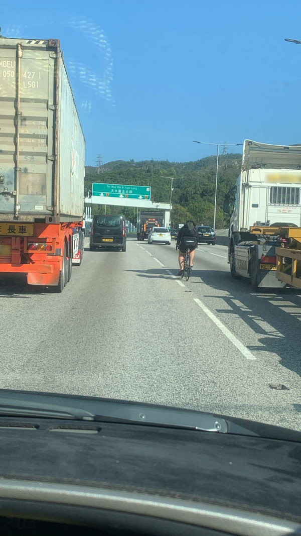一身著黑色上衣、短褲及拖鞋,背著黑色背囊的單車友於元朗公路騎行。(取自Facebook「車cam L」群組)