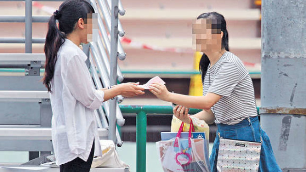 女「槍手」（右）交收作業，並收取酬勞，她手上挽着兩三袋代做的功課準備趕往交收。(相片來源：晴報)